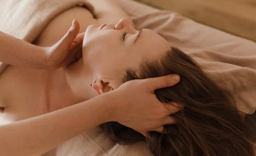 Une praticienne masse la tête et le visage d'une cliente lors d'une séance de massage crânien Shirotchampi ou de rituel Kobido à Auterive.