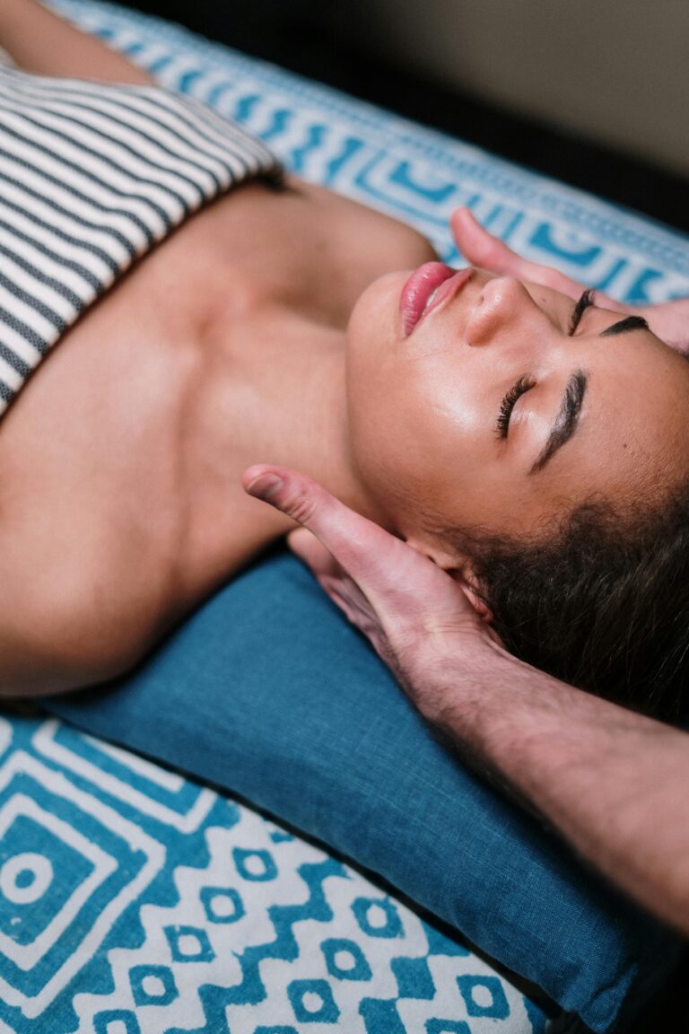 Une femme profite d'un massage du visage sur un coussin coloré lors d'une séance Les Ondoyantes, le massage Lomi-Lomi de Mass'Mie à Auterive.