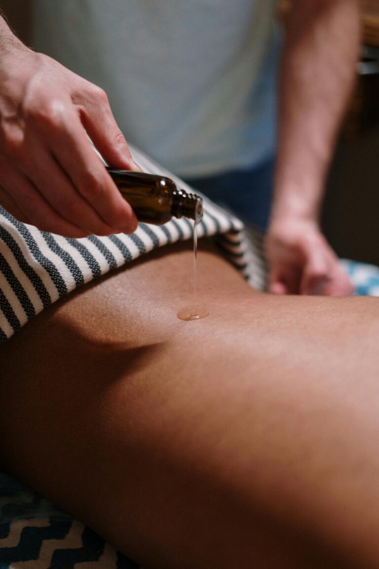 Une praticienne verse une huile de massage sur le dos d'une cliente lors d'une séance de massage Californien Les Sereines à Auterive.