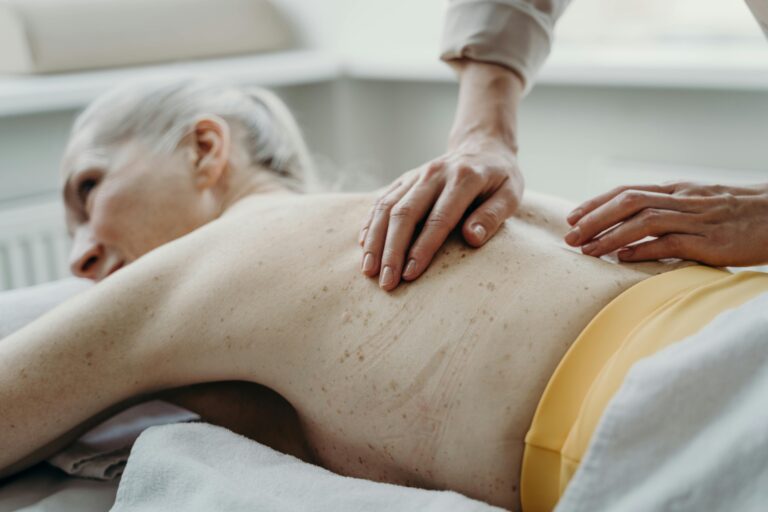 Une praticienne masse le dos d'une femme senior lors d'une séance Les Éternelles, le massage senior de Mass'Mie à Auterive.